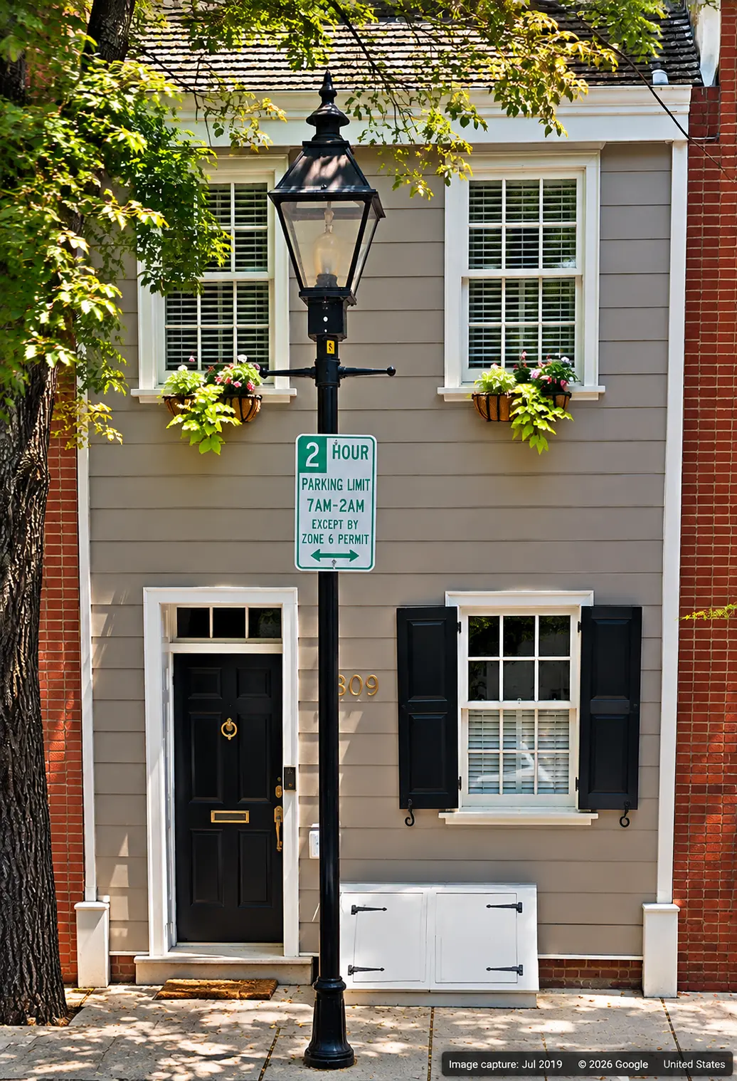 Narrow wooden house at 809 South Bond Street in Baltimore, with a black doorway, street lamp and Google image attribution.